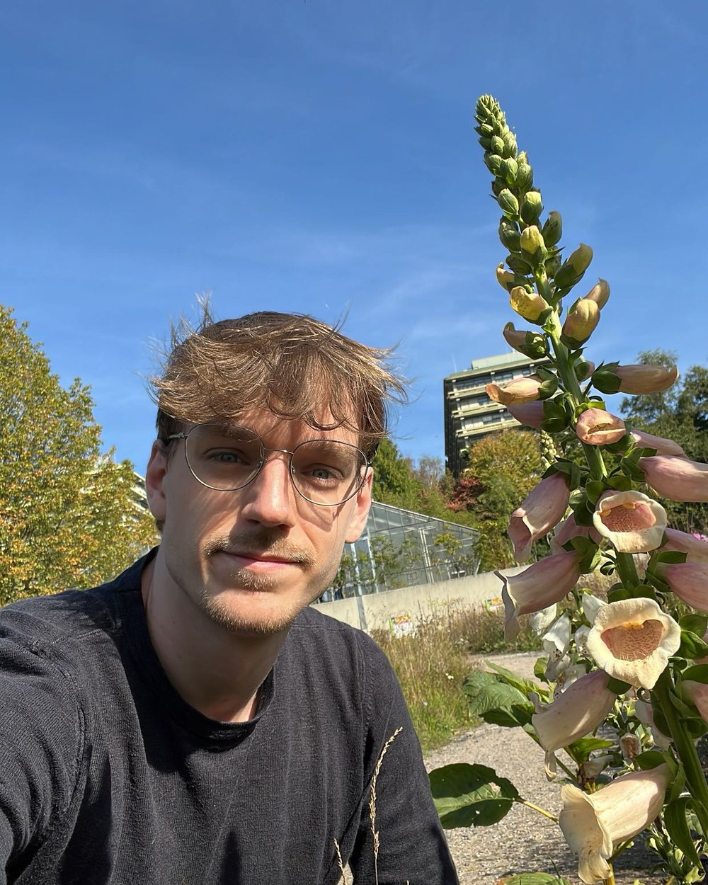 Benjamin Varbelow neben einem blühenden Fingerhut im Botanischen Garten der Ruhr-Universität Bochum